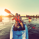 Photo shows a family kayaking happily as the sun sets